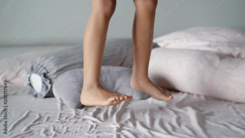 Closeup of little girl foot jumping on the bed at home. Shot during
