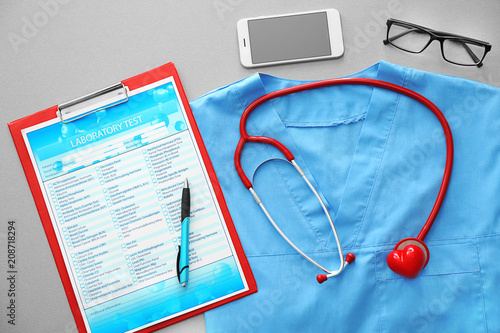Stethoscope with phone, laboratory test and blue doctor's uniform on table