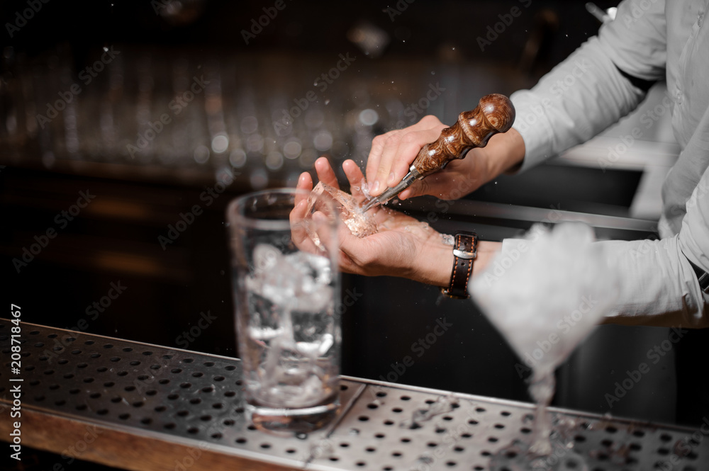 Professional bartender breaking an ice cube for the cocktail