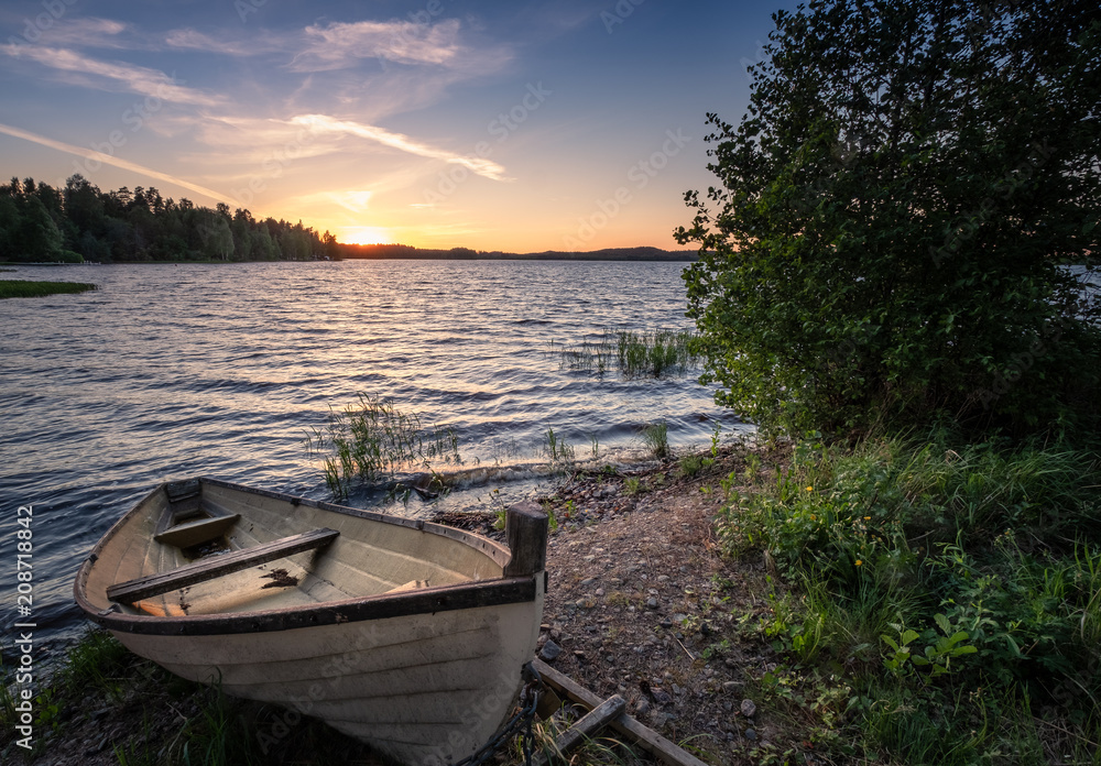 Obraz premium Scenic landscape with idyllic lake view and boat at summer evening in Finland