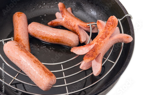 Photography Fried vienna sausages on lattice in frying pan closeup