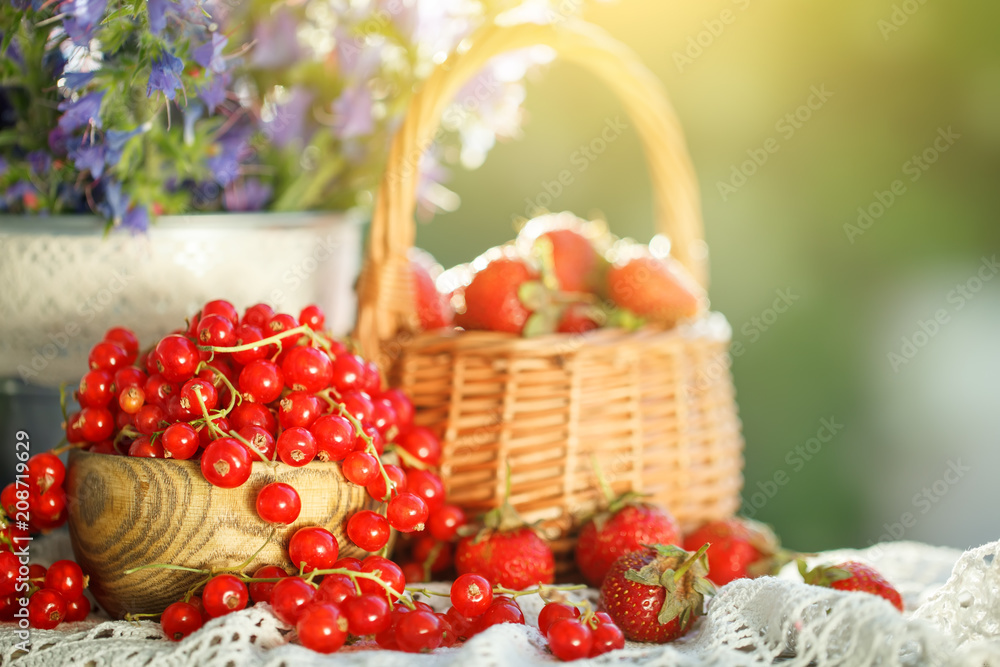 Ripe berries - red currants, strawberries, gooseberries on a wooden table in the summer garden. Harvest. Summer still life.
