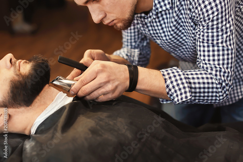 Professional barber working with client in hairdressing salon