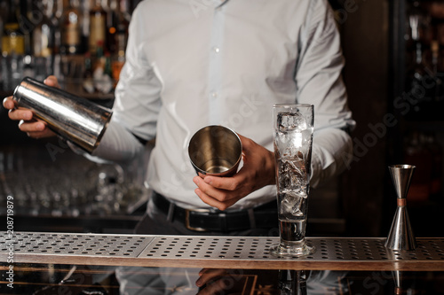 Bartender holding a cocktail shaker at the bar counter