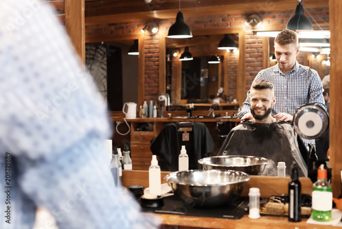 Professional barber working with client in hairdressing salon