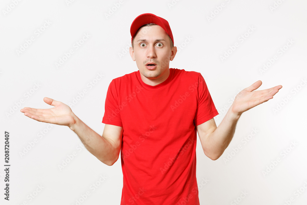 Delivery man in red uniform isolated on white background. Professional shocked young caucasian male in cap, t-shirt working as courier or dealer spreading hands gesture. Copy space for advertisement.