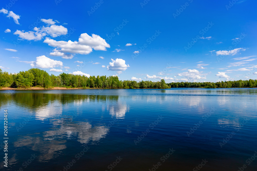 Beautiful summer landscape of river view with blue cloudy sky and wild forest reflections in water. Beautiful summer landscape of river view with blue cloudy sky and wild forest reflections in water.