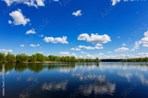 Fototapeta Naklejka Na Ścianę i Meble -  Beautiful summer landscape of river view with blue cloudy sky and wild forest reflections in water.