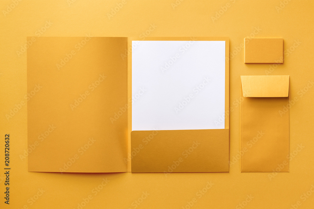 Naklejka premium Corporate stationery set mockup. Presentation folder, letterhead, envelope and business cards stack at golden textured paper background.