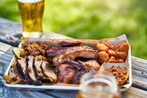 tray of smoked meats texas bbq style outside on picnic table on sunny summer day