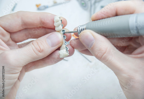 Dental technician manifacturing medical tooth prosthetic in laboratory