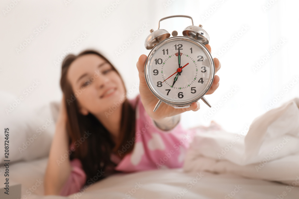 Young woman with alarm clock in bed. Early morning Young woman with alarm clock in bed. Early morning