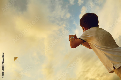 Child boy with a kite in the sky with clouds in summer. © Studio Romantic