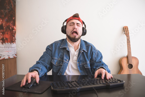 Gamer with headphones sitting at home and crying. Sad man plays a video game at home behind a computer in a cozy room. photo