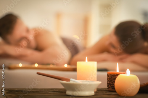 Spa composition with candles and relaxing couple on background