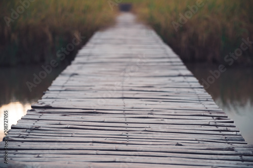 An old bamboo wooden bridge above the river and rice field