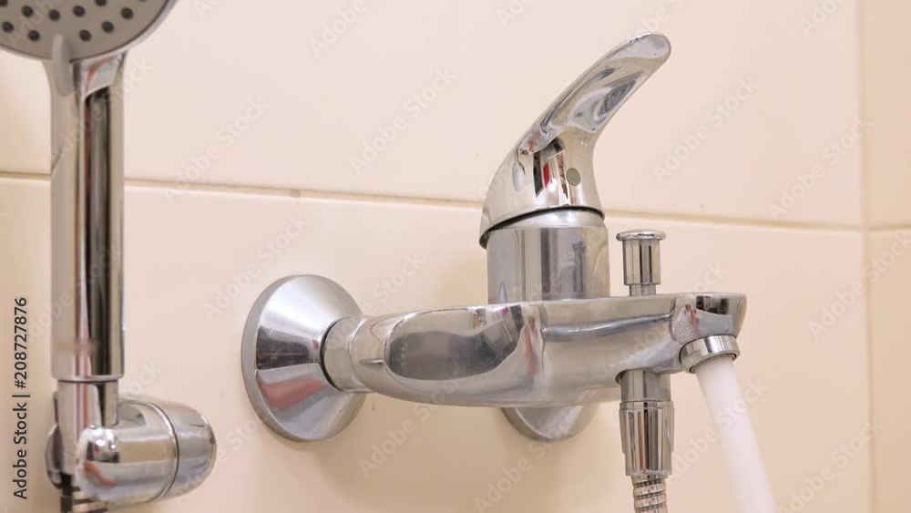 A woman turns on and off a bathtub faucet with her foot closeup Stock