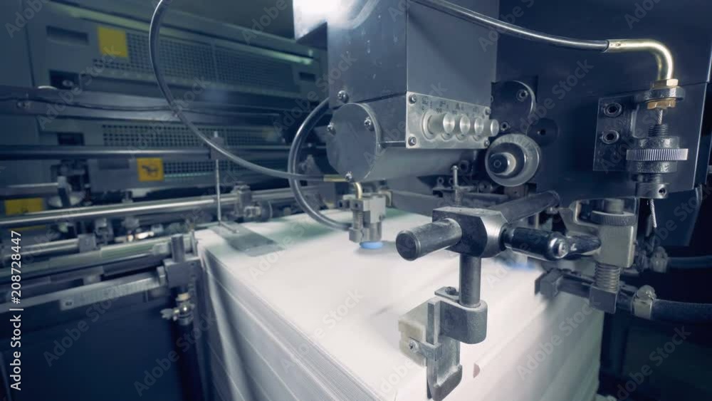 A machine divides lot of paper sheets, close up. Paper production process. A machine divides lot of paper sheets, close up. Paper production process.