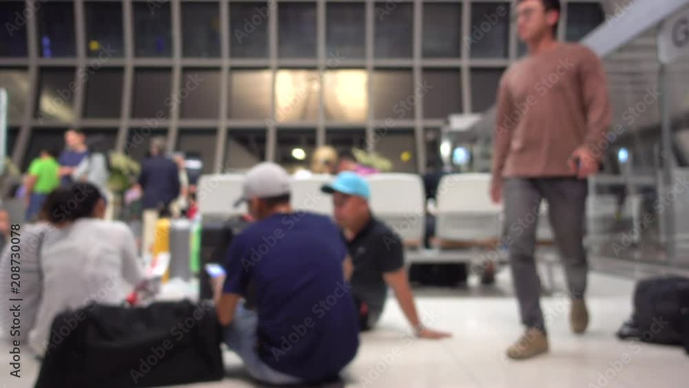 Blurred defocused image of many people sitting and waiting for the chair in gate waiting zone at the airport. Blurry background of travelers in terminal departure check-in at the international airport Blurred defocused image of many people sitting and waiting for the chair in gate waiting zone at the airport. Blurry background of travelers in terminal departure check-in at the international airport
