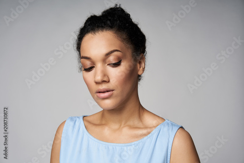 Closeup portrait of beautiful serene mixed race caucasian - african american woman looking down  isolated on gray background