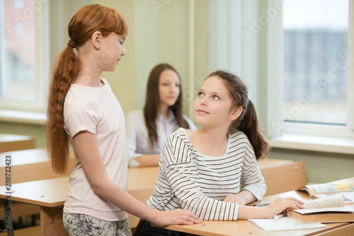 3 student girls are sitting at a Desk