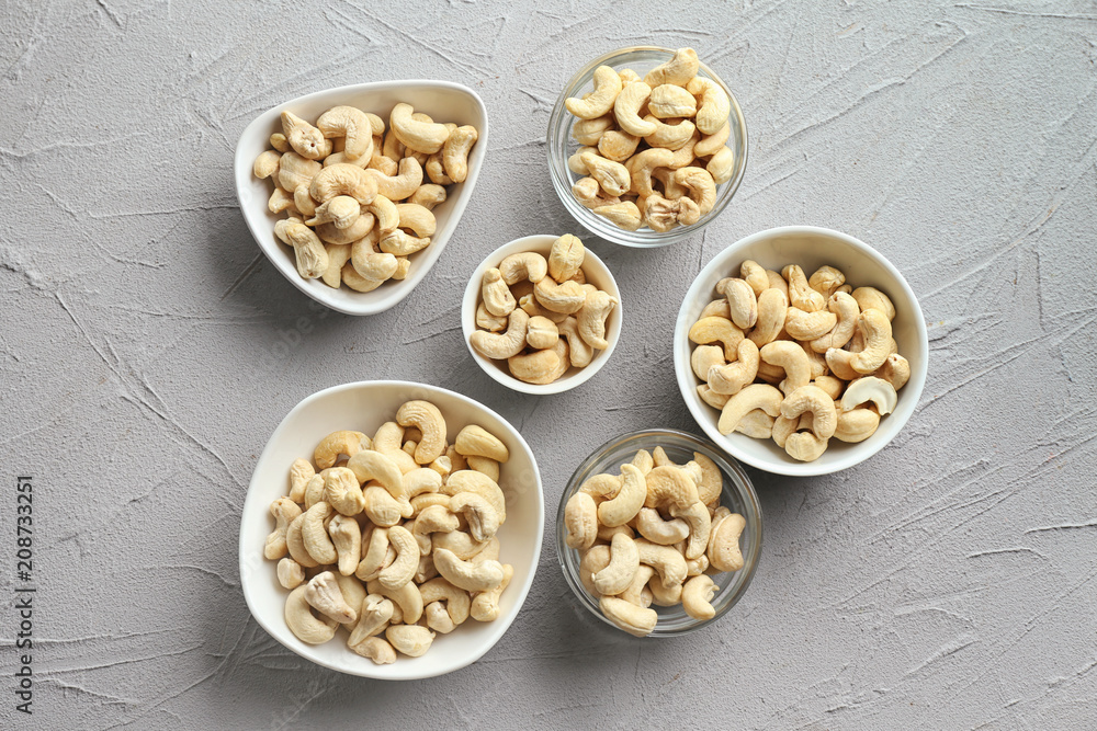 Bowls with tasty cashew nuts on light background