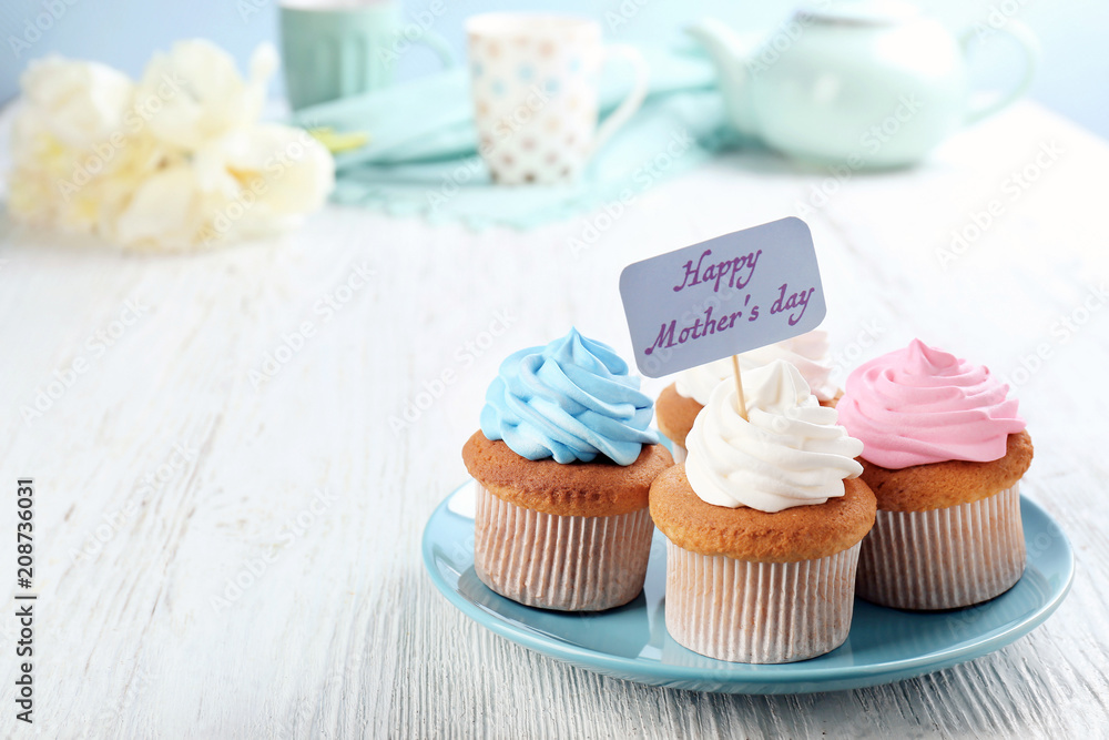 Tasty cupcakes and topper pick with words HAPPY MOTHER'S DAY on table Tasty cupcakes and topper pick with words HAPPY MOTHER'S DAY on table