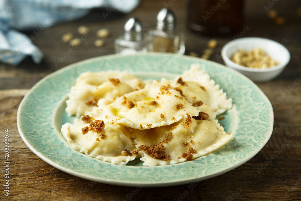Homemade ravioli with fried bread crumbs, soft cheese and pine nuts