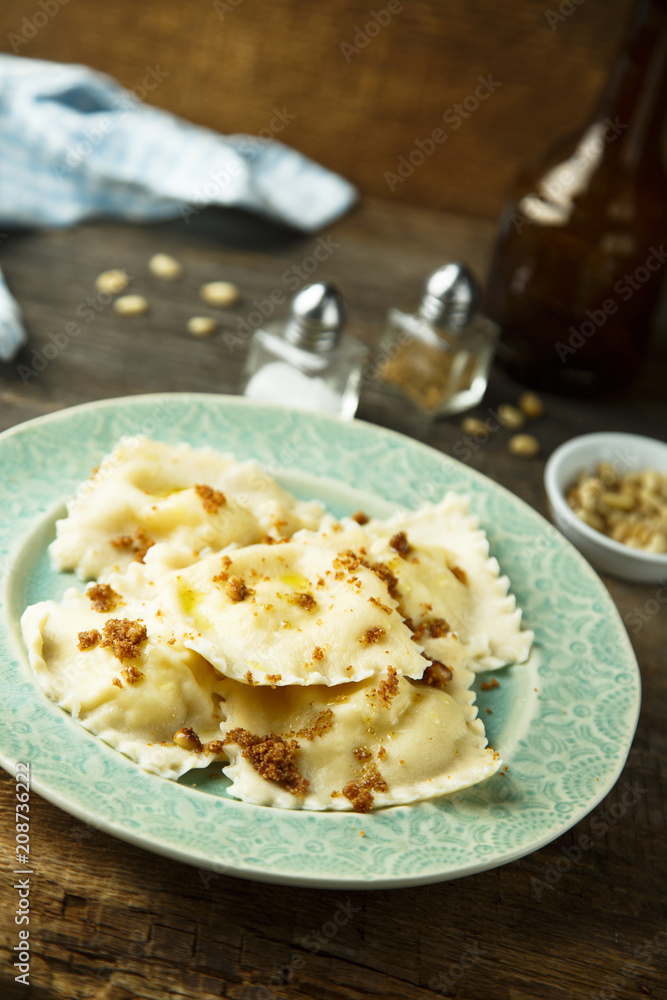 Homemade ravioli with fried bread crumbs, soft cheese and pine nuts