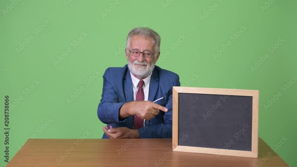 Handsome senior bearded businessman against green background Handsome senior bearded businessman against green background