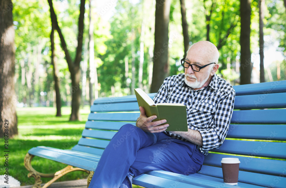 Elderly man in casual reading outdoors Elderly man in casual reading outdoors