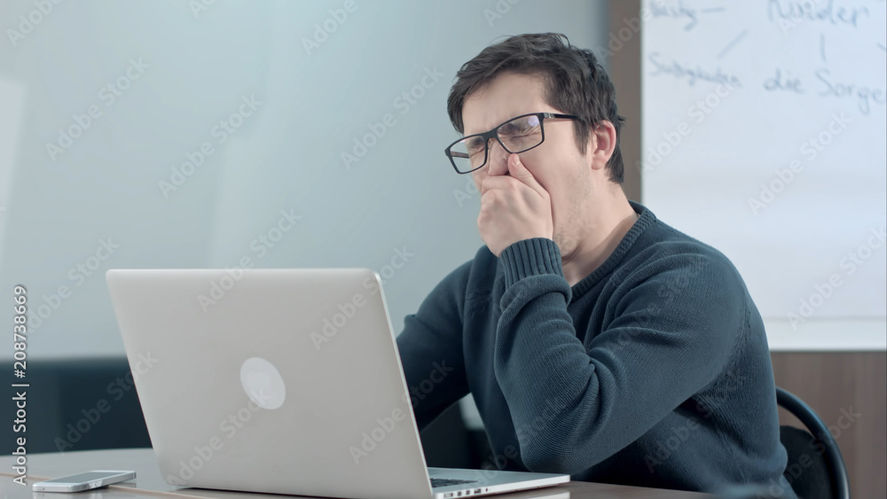 Tired student thinking about his work and using laptop Tired student thinking about his work and using laptop