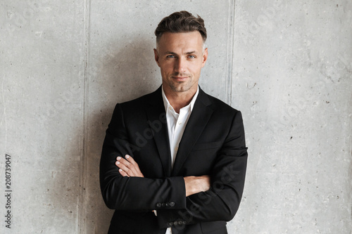 Фотография Handsome man dressed in suit holding arms folded