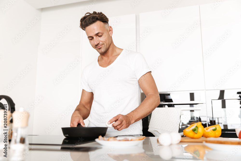 Attractive man cooking eggs for breakfast Attractive man cooking eggs for breakfast