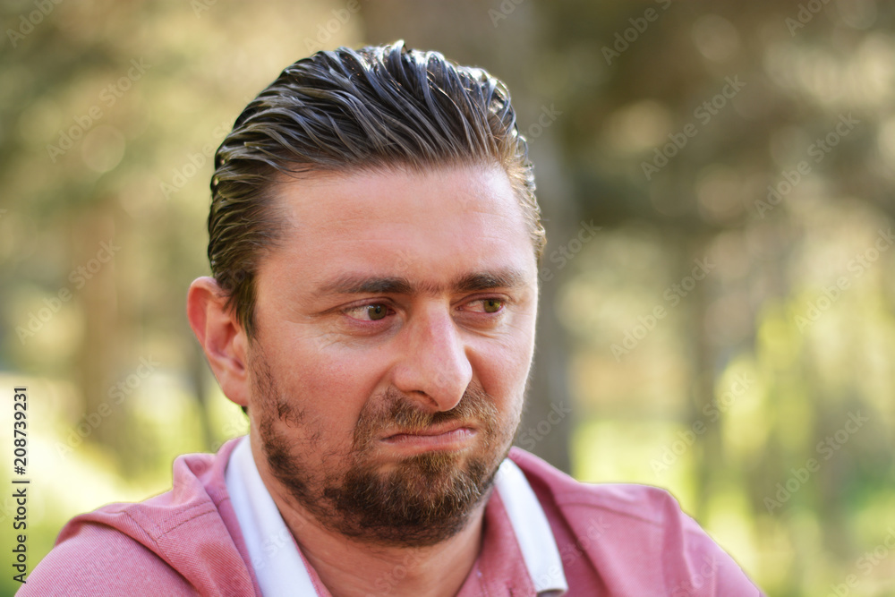 Young man's outdoors portrait looking at the camera with natural green background. Neutral, happy, sad, angry, disgust, fear, surprise Facial Emotions. Young man's outdoors portrait looking at the camera with natural green background. Neutral, happy, sad, angry, disgust, fear, surprise Facial Emotions.