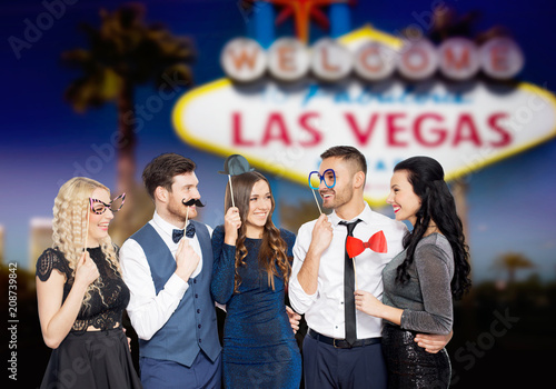 Photography celebration, fun and holidays concept - happy friends posing with party props ov