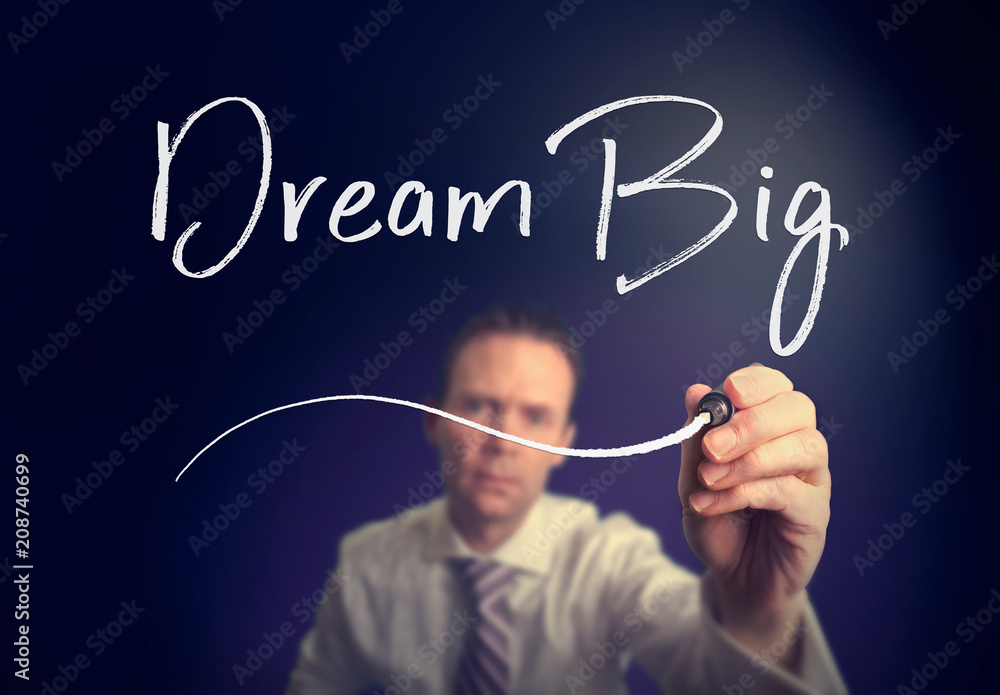 A businessman writing a Dream Big concept with a white pen on a clear screen. A businessman writing a Dream Big concept with a white pen on a clear screen.
