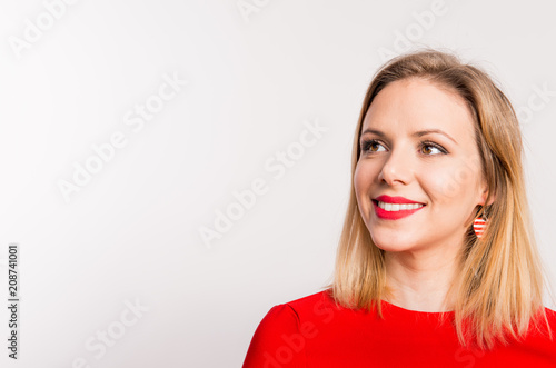 Portrait of a young beautiful woman dressed in red in studio. © Halfpoint