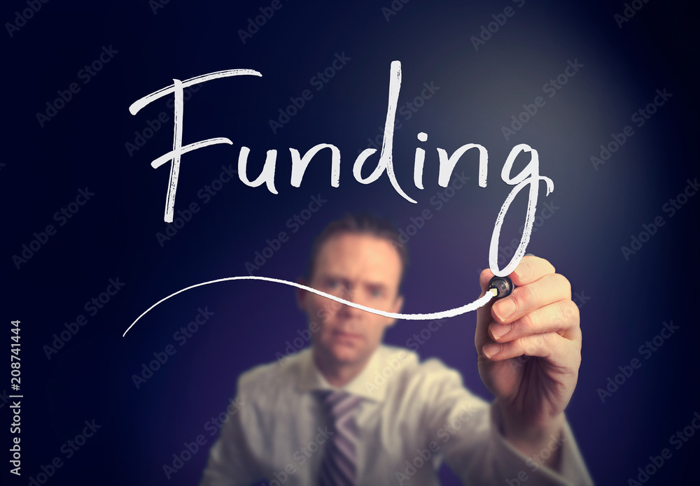 A businessman writing a Funding concept with a white pen on a clear screen. A businessman writing a Funding concept with a white pen on a clear screen.