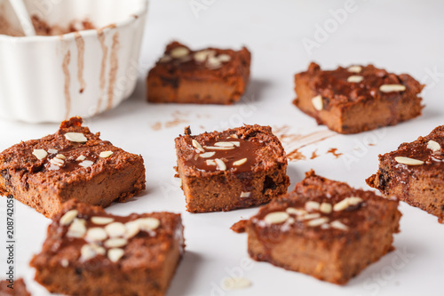 Pieces of vegan pumpkin brownie on white table. Healthy vegan food concept.