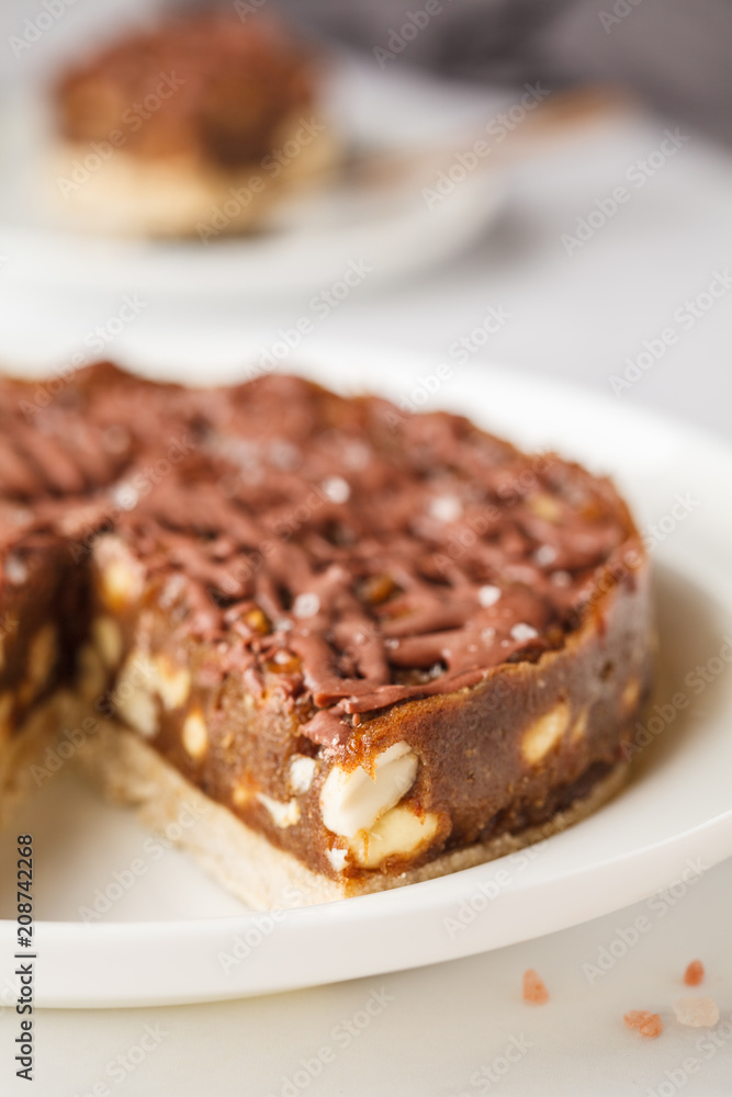 Raw vegan chocolate cake with nuts and chocolate in white plate. Healthy vegan food concept. Raw vegan chocolate cake with nuts and chocolate in white plate. Healthy vegan food concept.