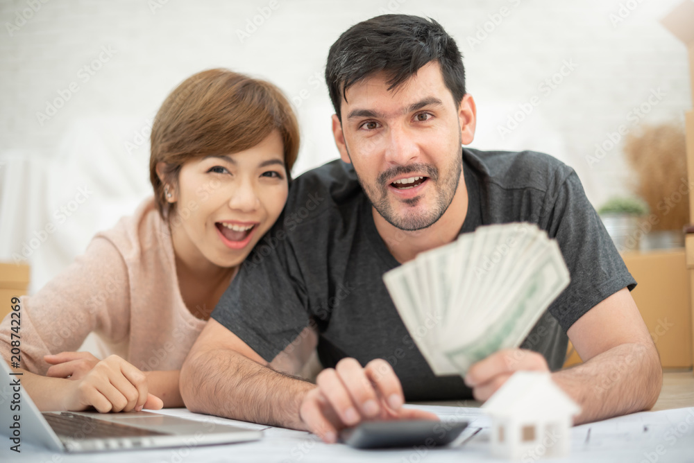 Happy couple holding money and calculating their budget. Happy couple holding money and calculating their budget.