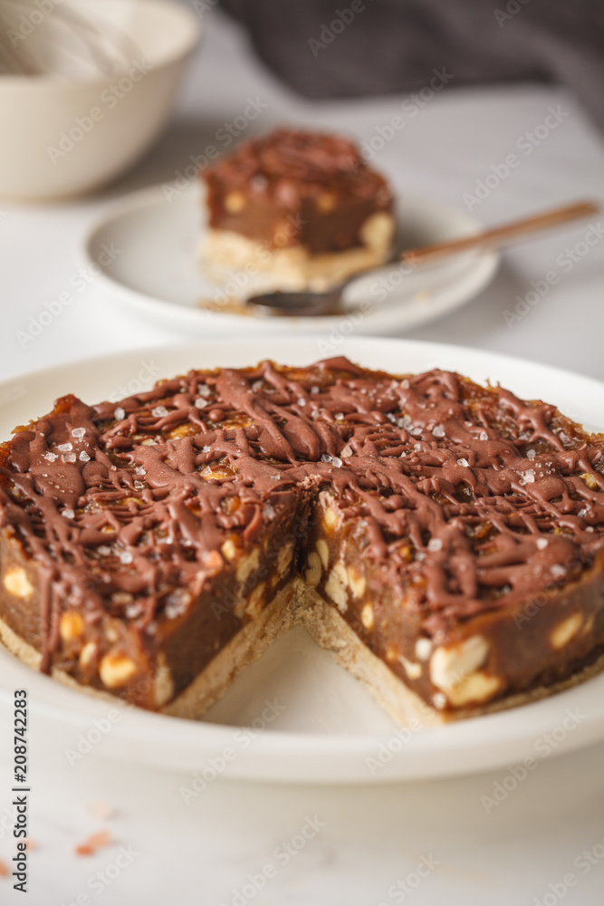 Raw vegan chocolate cake with nuts and chocolate in white plate. Healthy vegan food concept. Raw vegan chocolate cake with nuts and chocolate in white plate. Healthy vegan food concept.