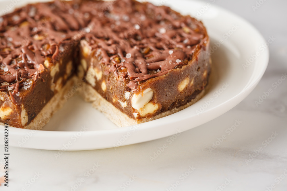 Raw vegan chocolate cake with nuts and chocolate in white plate. Healthy vegan food concept. Raw vegan chocolate cake with nuts and chocolate in white plate. Healthy vegan food concept.