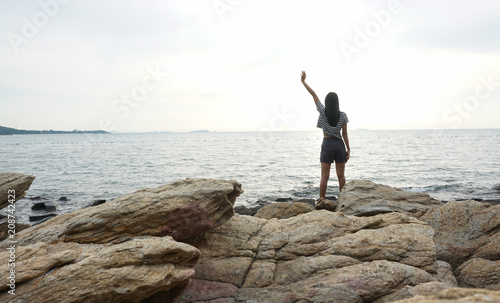Young woman standing on rock looking at sea, sad and depressed.