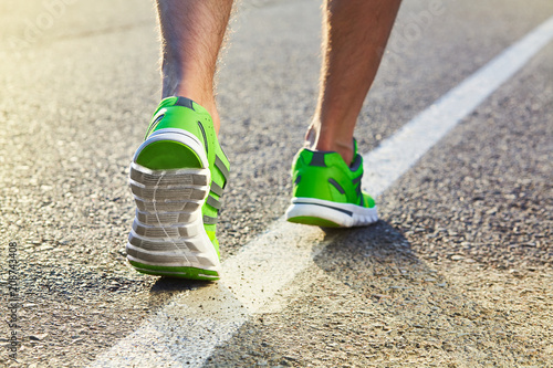 Runner man feet running on road closeup on shoe. Male fitness athlete jogger workout in wellness concept. Male athletes in running shoes. Jogging