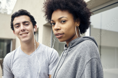 Friends listening to music together with earphones, portrait photo