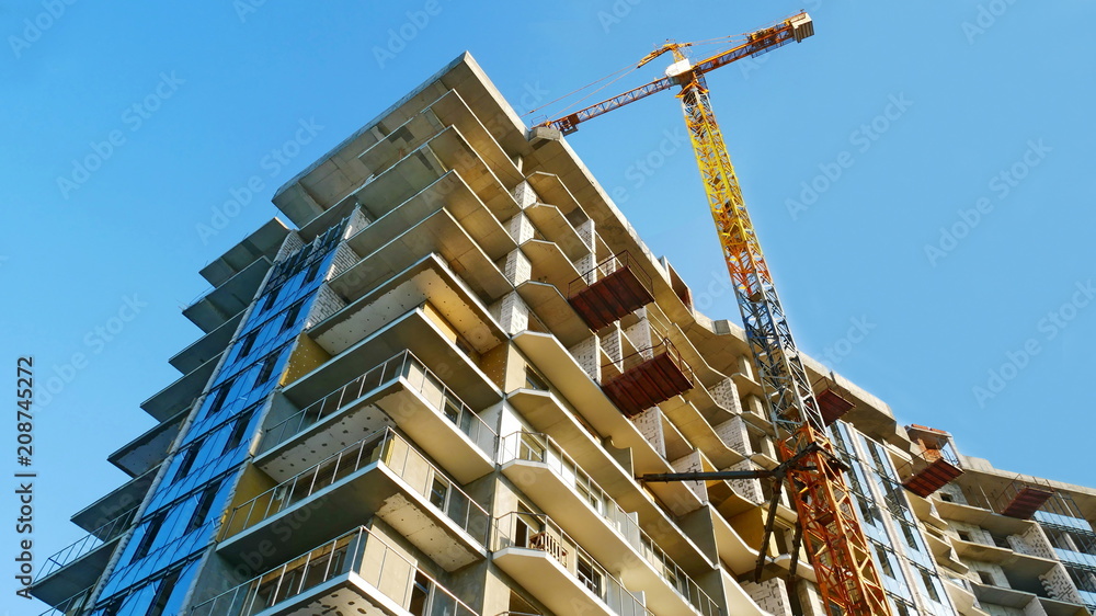 Industrial crane near building against blue sky. Construction site.
