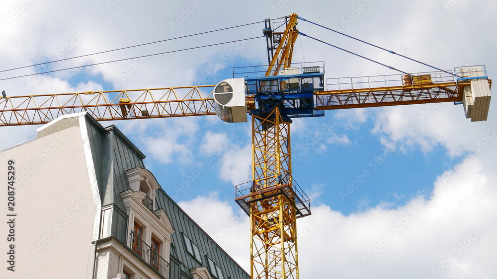 Industrial crane near building against blue sky.