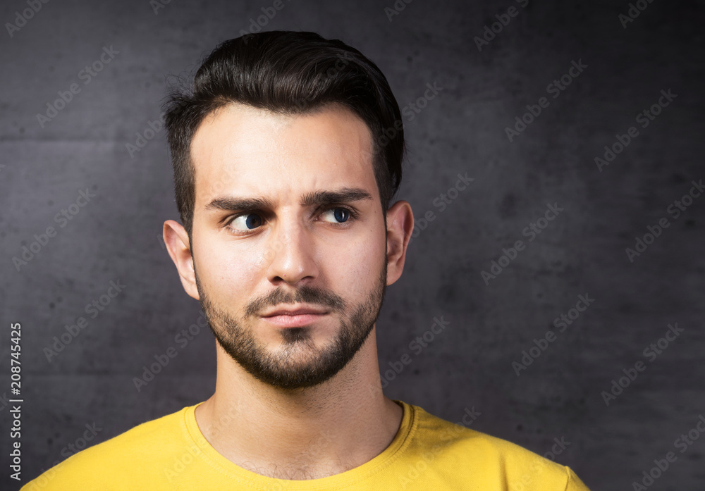 Portrait of thoughtful young man standing by the wall. Portrait of thoughtful young man standing by the wall.